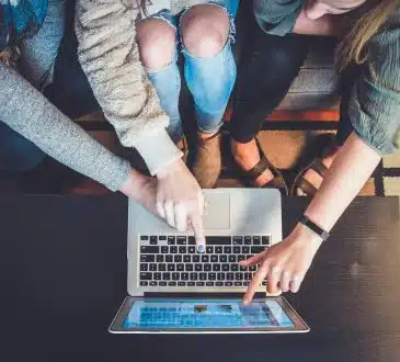 three person pointing the silver laptop computer