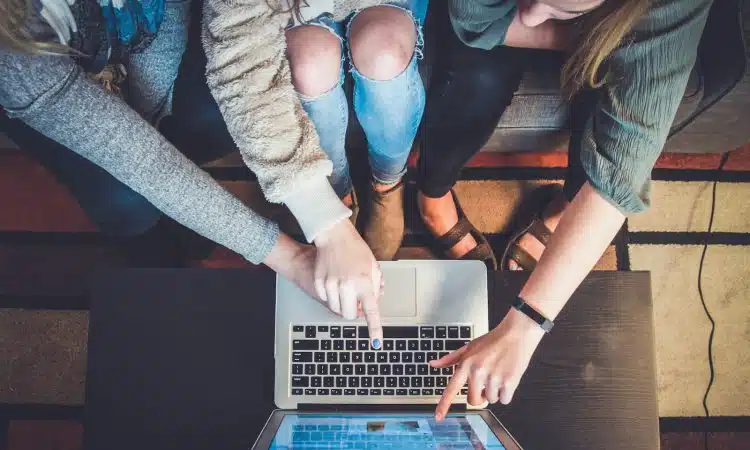 three person pointing the silver laptop computer