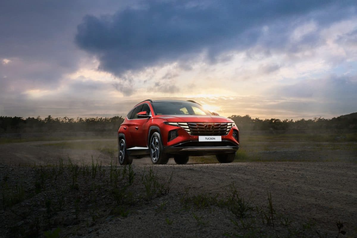 a red suv driving down a dirt road