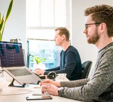 man sitting on chair wearing gray crew-neck long-sleeved shirt using Apple Magic Keyboard