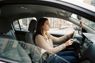Jeune femme débutante au volant d'une voiture sans permis en ville, mains sur le volant, expression concentrée
