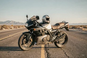 Moto Kawasaki GPz900R de Top Gun garée sur une route côtière désertique évoquant l'esthétique du film culte