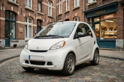 Voiture sans permis d'occasion garée dans une rue pavée de Lille avec architecture flamande en arrière-plan